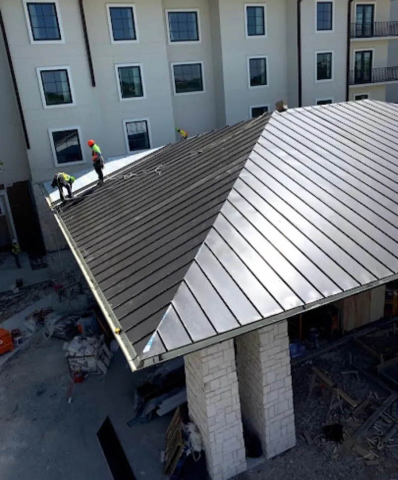 Crew installing standing seam metal roof panels on a commercial project in Middlebury